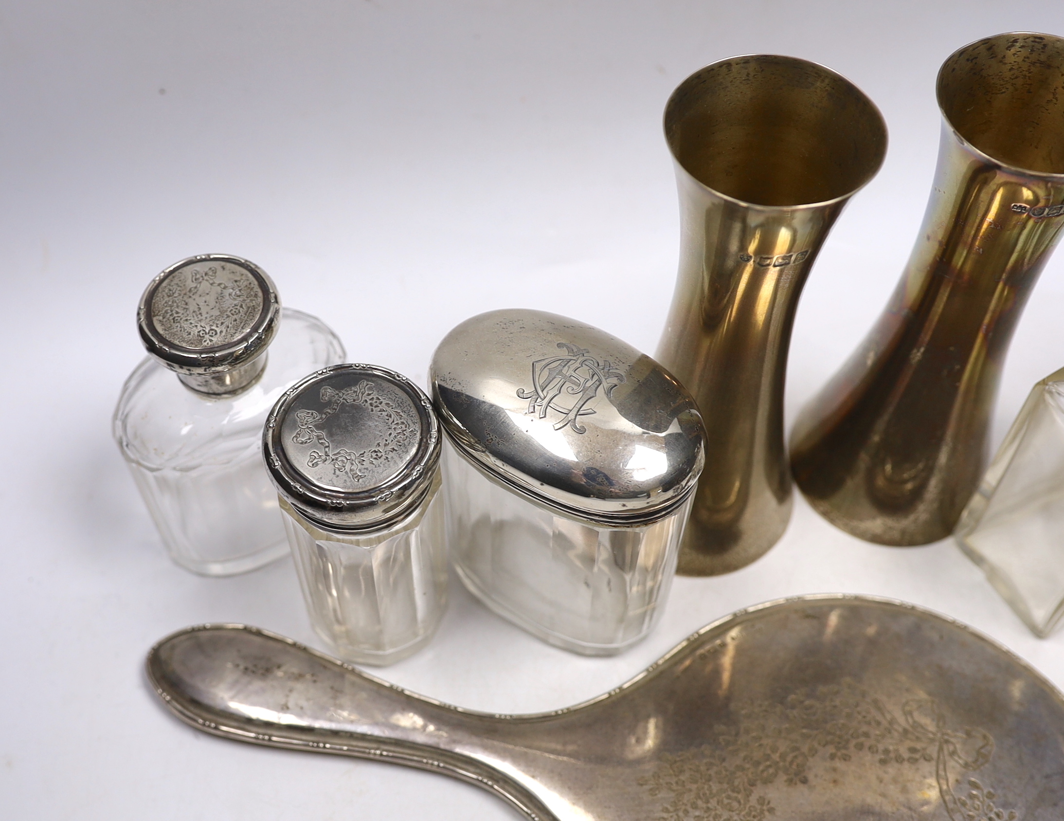 A pair of Edwardian silver waisted spill vase, London, 1907, 15cm, six silver mounted glass toilet jars, a silver mounted hand mirror and comb.